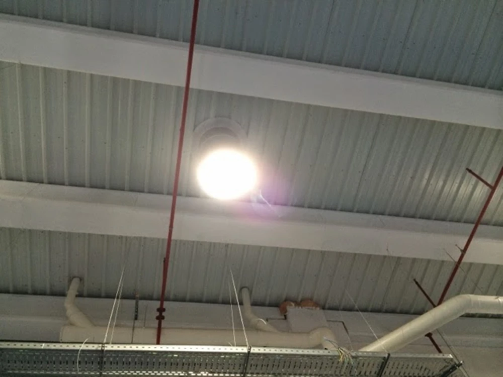 Vista del techo industrial con tuberías de protección contra incendios y luminaria encendida, instalación realizada por Extintores A2J en Sevilla.