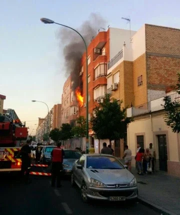 Incendio en un edificio de viviendas en Sevilla, con llamas y humo saliendo de una fachada y bomberos interviniendo en la calle.